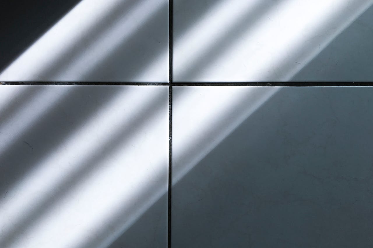 A minimalist image capturing sunlight casting shadows on tiled flooring.